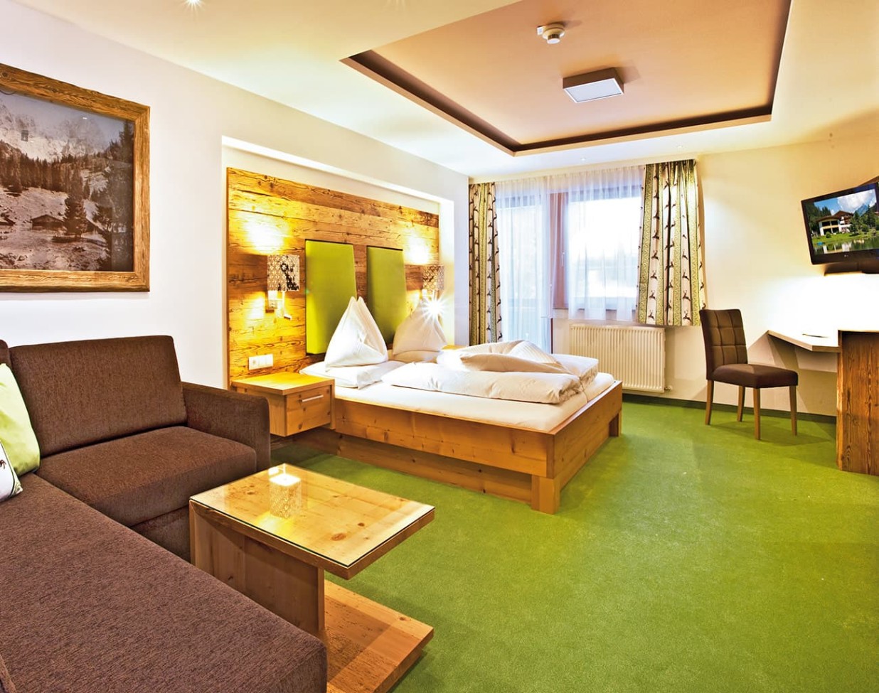 Doppelzimmer mit Sitzgelegenheit und Balkon im Alpenhof Naturglück in Filzmoos